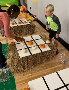 two children are playing with pumpkins on hay bales in an indoor play area