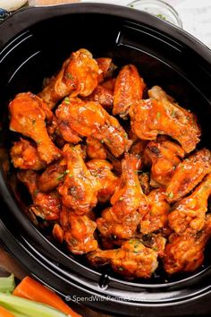 chicken wings in the slow cooker with carrots and celery next to it