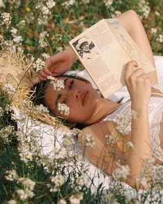 a woman laying in the grass reading a book