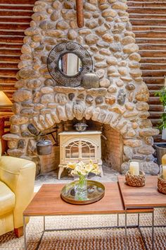 a living room filled with furniture and a fire place in front of a stone wall