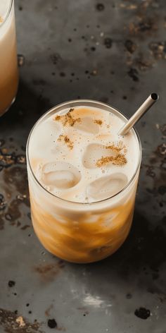 two glasses filled with drinks sitting on top of a black table next to each other