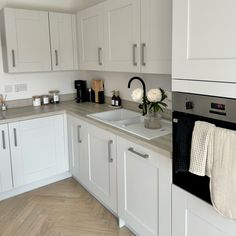 a kitchen with white cabinets and gray counter tops is pictured in this image, there are flowers on the sink