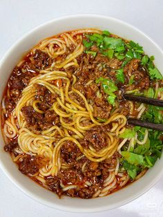 a white bowl filled with noodles and meat