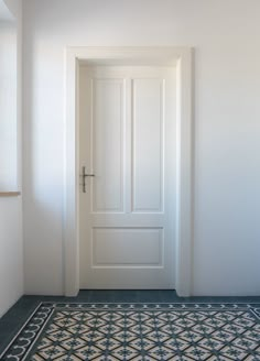 an empty room with a white door and black tile flooring on the side wall