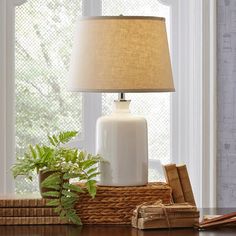 a white lamp sitting on top of a wooden table next to a potted plant