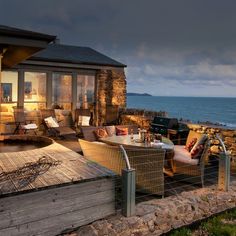 an outdoor living area with wicker furniture and ocean view in the background at dusk