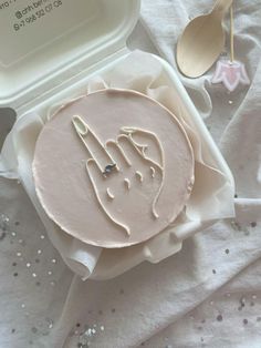 a cake with icing on it sitting in a container next to spoons and utensils