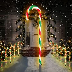 a candy cane in front of a house decorated for christmas