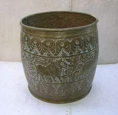 an ornate metal bowl is sitting on a white surface