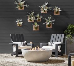 an outdoor fire pit surrounded by chairs and potted plants