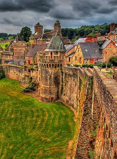 an aerial view of the castle and surrounding buildings, with dark clouds in the sky