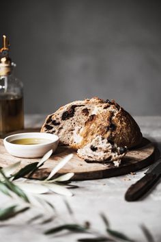 a loaf of bread sitting on top of a cutting board next to a bowl of olive oil