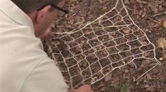 a man in white shirt and black glasses looking at something on the ground with net