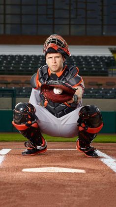 a baseball player squatting on the field with his catchers mitt in hand