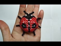 a ladybug beaded brooch sitting on someone's hand