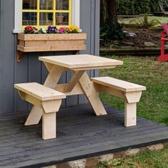 a wooden picnic table sitting next to a window