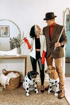 a man and woman standing next to two dogs in front of a mirror with one dog on the floor