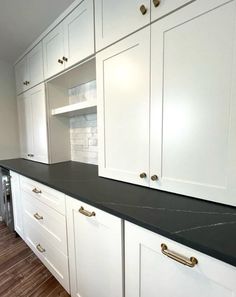 an empty kitchen with white cabinets and black counter tops in the middle of the room