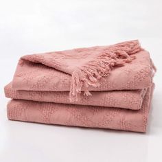 two pink towels stacked on top of each other in front of a white background,