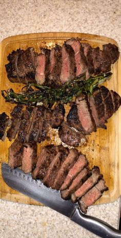 steak and asparagus on a wooden cutting board with a knife next to it