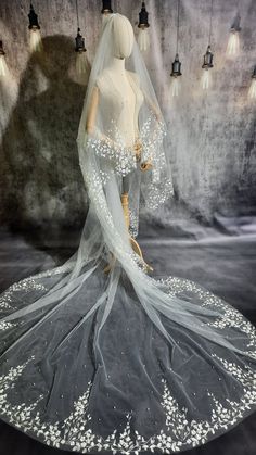 a mannequin wearing a wedding dress with white flowers on the skirt and veil