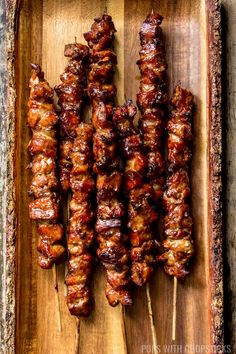 several skewers of meat sitting on top of a wooden tray