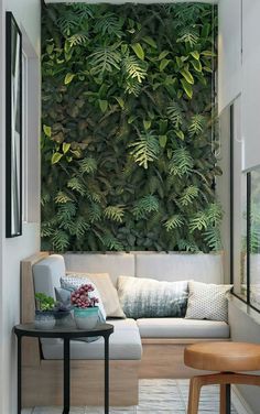 a living room with a couch and table in front of a large green plant wall