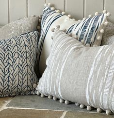 three pillows with pom poms on them are lined up against a white wall