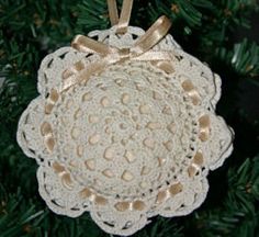 a crocheted doily ornament hanging from a christmas tree with gold ribbon