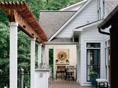 an outdoor patio with white walls and wood flooring next to a large wooden pergoline