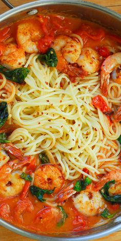 pasta with shrimp, spinach and tomato sauce in a pan on a wooden table