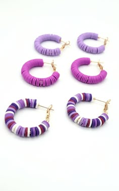 four pairs of hoop earrings with purple and white stripes on each earring, all in different colors