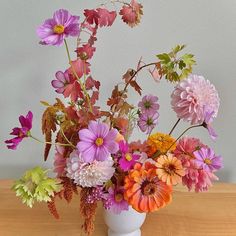 a white vase filled with lots of colorful flowers