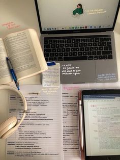 an open laptop computer sitting on top of a desk next to a book and headphones