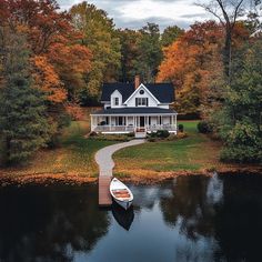 a boat sits on the water in front of a large white house with a dock