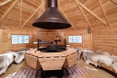 the inside of a log cabin with wood flooring and walls, including a stove