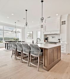 a large kitchen with white cabinets and wooden flooring next to a dining room table