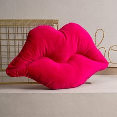 a large pink pillow sitting on top of a white table next to a wire cage