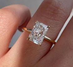 a close up of a person's hand with a diamond ring on their finger