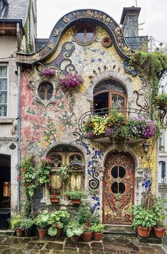 a building with many windows and flowers on the outside, along with potted plants