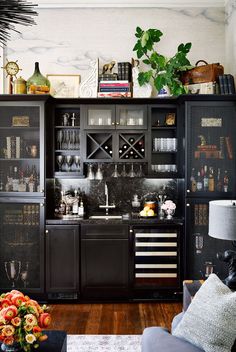 a living room filled with furniture and lots of bottles on top of the cabinet doors