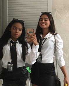 two young women dressed in black and white taking a selfie with their cell phones