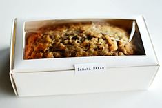 a banana bread in a white box on a table with a label that says banana bread