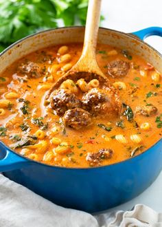 a blue pot filled with pasta and meatballs in tomato sauce, garnished with parsley