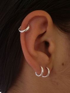 a close up of a person's ear with two small hoops on it