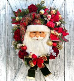 a christmas wreath with santa claus's head and red flowers on the front door