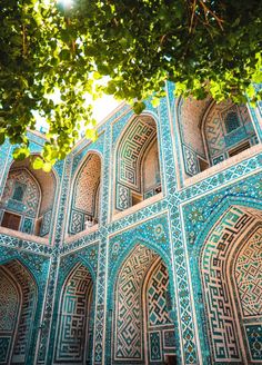 an intricately designed building with blue tiles and green trees in the foreground, on a sunny day