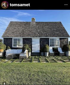 a black and white house with potted plants on the front lawn in front of it