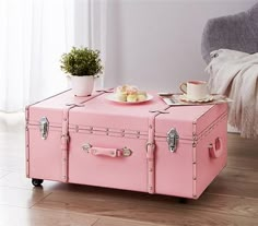 a pink trunk coffee table sitting on top of a hard wood floor next to a chair