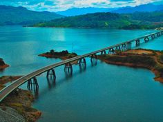 an aerial view of a bridge spanning the width of a body of water with mountains in the background